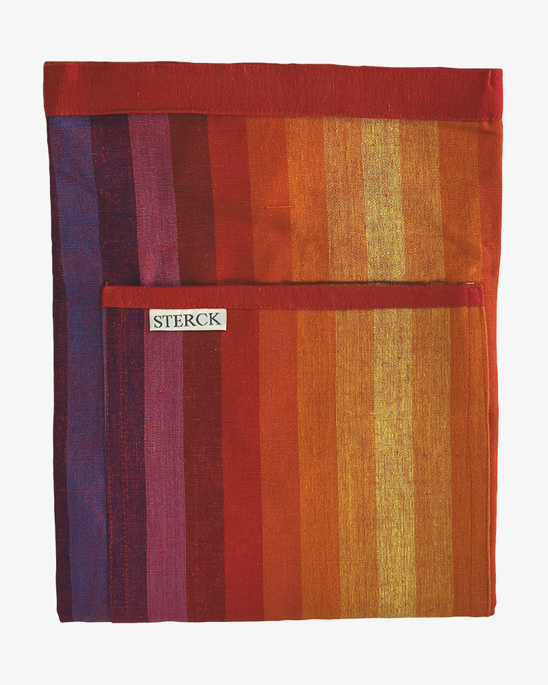 close up photo of a cotton half apron, with a red trimmed detailing front pocket branded by sterck.