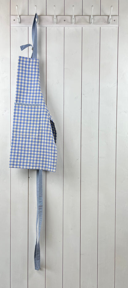 Blue gingham apron for children with large front pocket and adjustable neck strap. Sterck & Co.