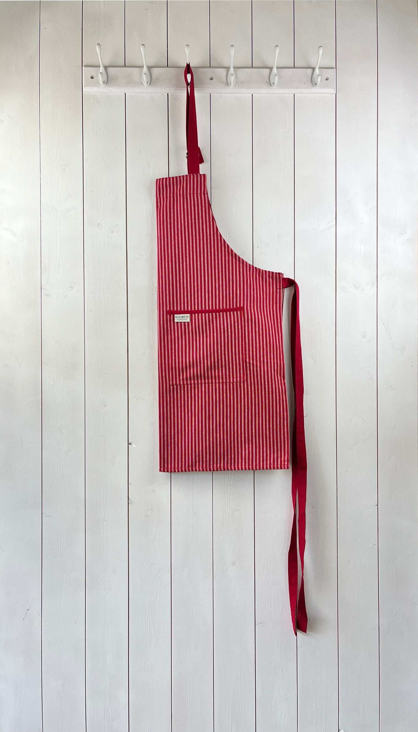red striped cotton apron with double front pockets, red ties and adjustable neck strap. sterck & co. drum red.