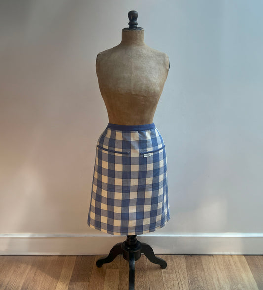 A classically checked blue and off-white half apron from Sterck & Co. Modelled by a vintage mannequin.