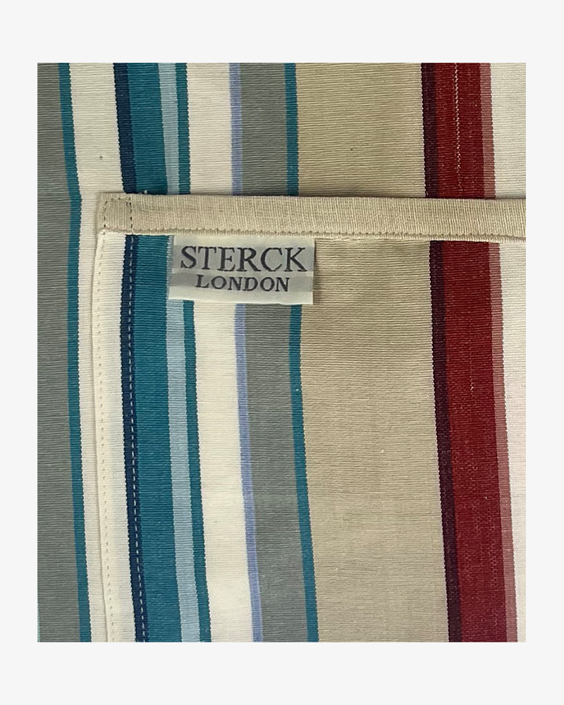 a vibrant striped cotton apron with double front pockets, cream ties and adjustable neck strap. sterck & co. close up of fabric and pocket detailing.