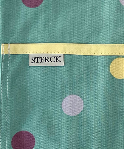 Duck egg blue cotton apron with purple, yellow and mauve spots, yellow ties and adjustable neck strap. Close up of fabric and pocket detail.