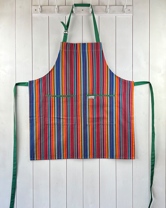 A stripy cotton apron with prominent ticking, two front pockets and adjustable green straps.