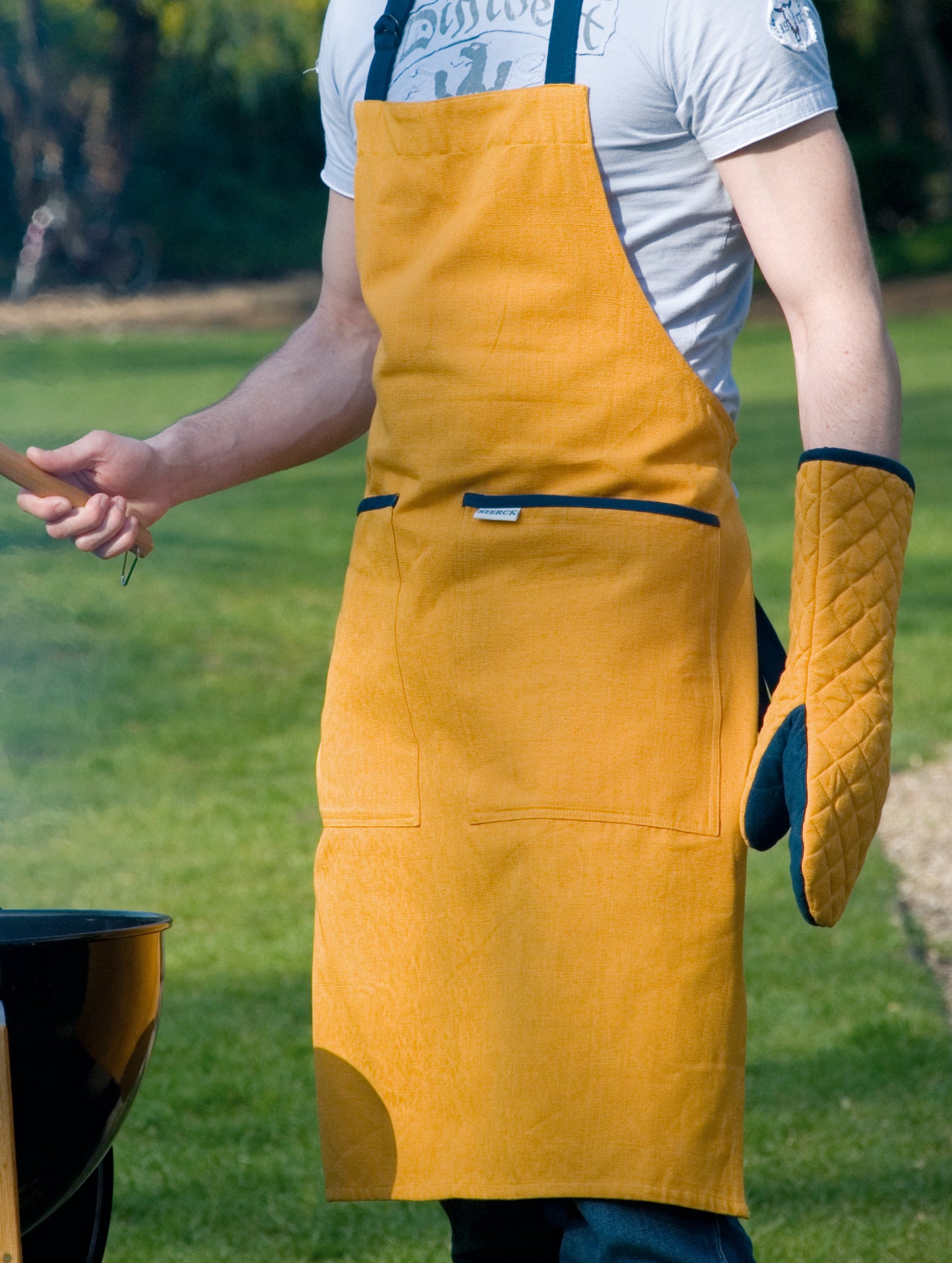 lithe young fellow bbqing with yellow and aqua-green oven gauntlet from sterck & co.
