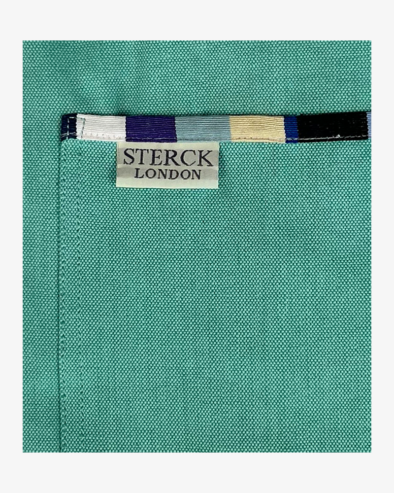 a mint green cotton apron with stripy detailing, double front pockets, stripy ties and adjustable neck strap. sterck & co. close up of fabric and pocket detailing.