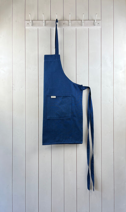Sky blue cotton apron with double front pockets and adjustable neck strap. Sterck & Co.