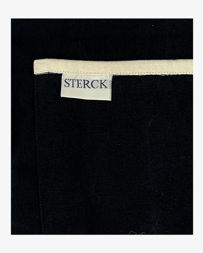 Black apron with cream detailing and ties. Double front pockets and adjustable neck strap. Sterck and Co. Close up of pocket detailing and fabric.