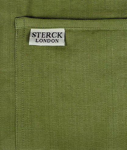 Moss green cotton apron with double front pockets and adjustable neck strap. Sterck & Co. Close up of fabric and pocket detailing.