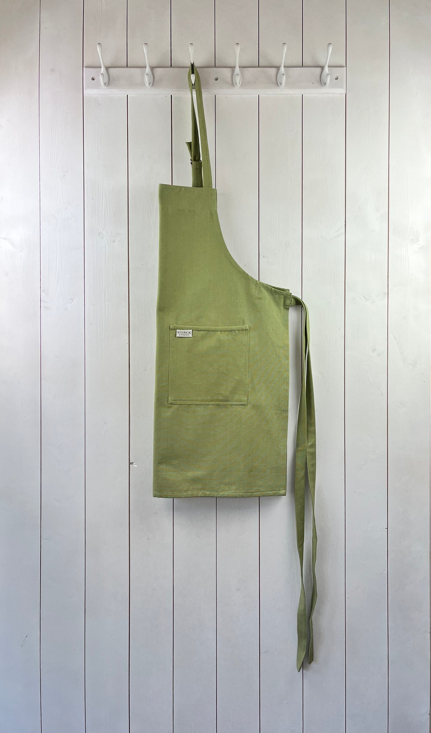 moss green cotton apron with double front pockets and adjustable neck strap. sterck & co.