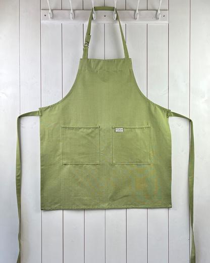 Moss green cotton apron with double front pockets and adjustable neck strap. Sterck & Co.
