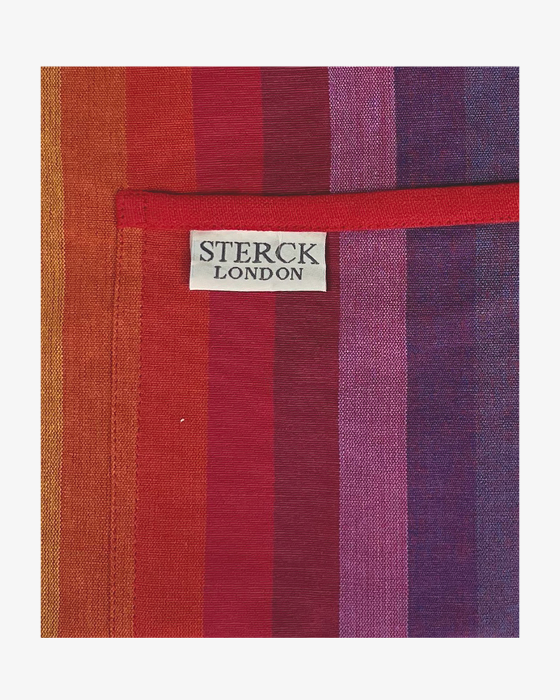chihuahua rainbow striped cotton apron with double front pockets, red ties and adjustable neck strap. sterck & co. close up of fabric and pocket detailing.