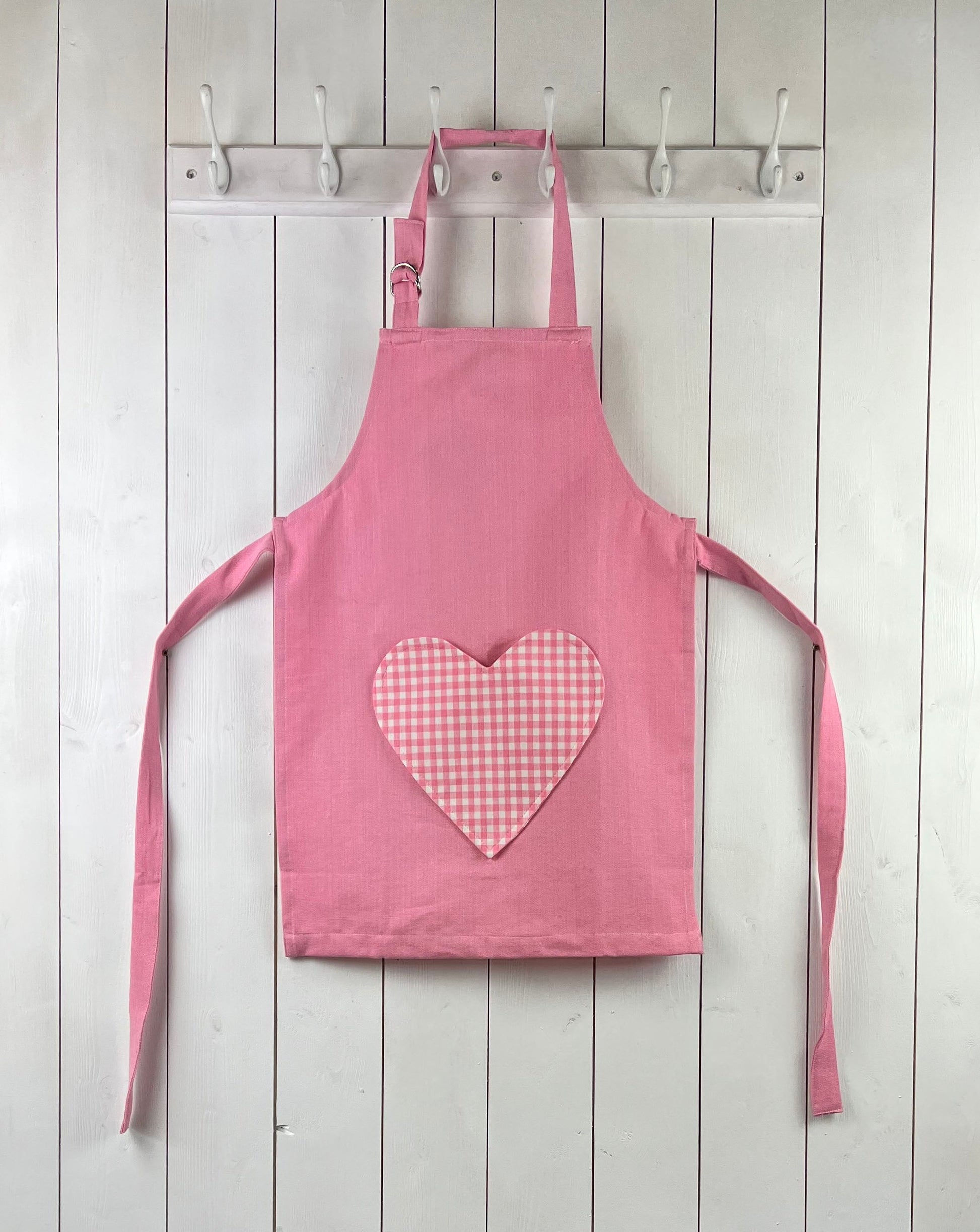 Pink child apron with gingham heart shaped pocket. From Sterck & Co.