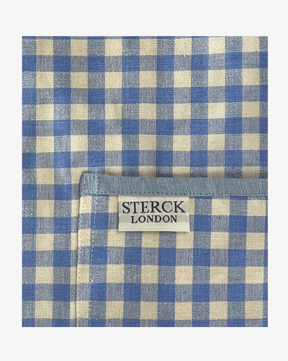 Blue gingham apron for children with large front pocket and adjustable neck strap. Sterck & Co. Close up of fabric and pocket detailing.