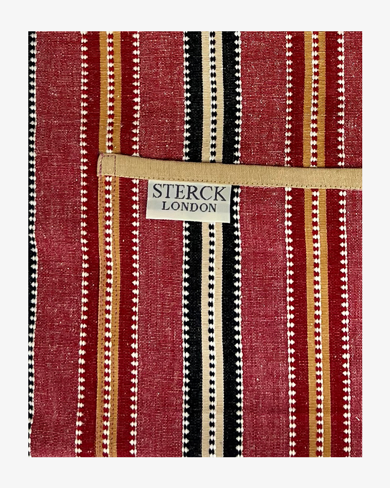 chimichanga dusky red striped cotton apron with double front pockets and adjustable neck strap. sterck & co. close up of fabric and pocket detailing.