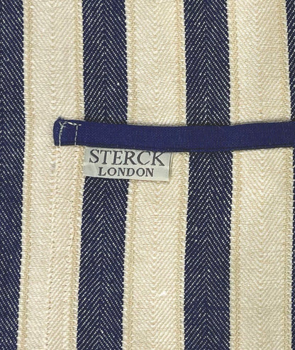 A classic wide striped cotton apron with double front pockets and adjustable neck tie. From Sterck & Co. Close up of fabric and pocket detailing.