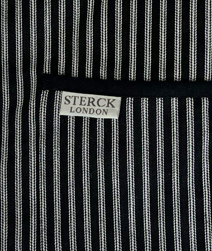 Black and white striped cotton apron with double front pockets, black ties and adjustable neck strap. Sterck & Co. Drum black. Cloe up of fabric and pocket detailing.