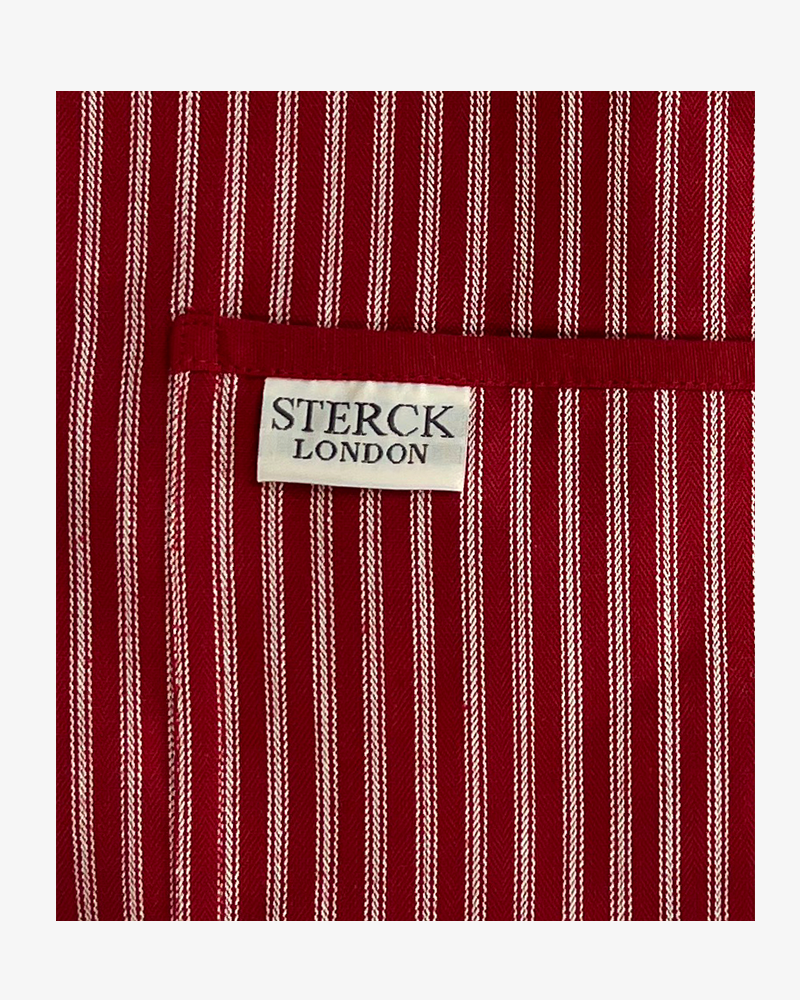 red striped cotton apron with double front pockets, red ties and adjustable neck strap. sterck & co. drum red. close up of fabric and pocket detailing.