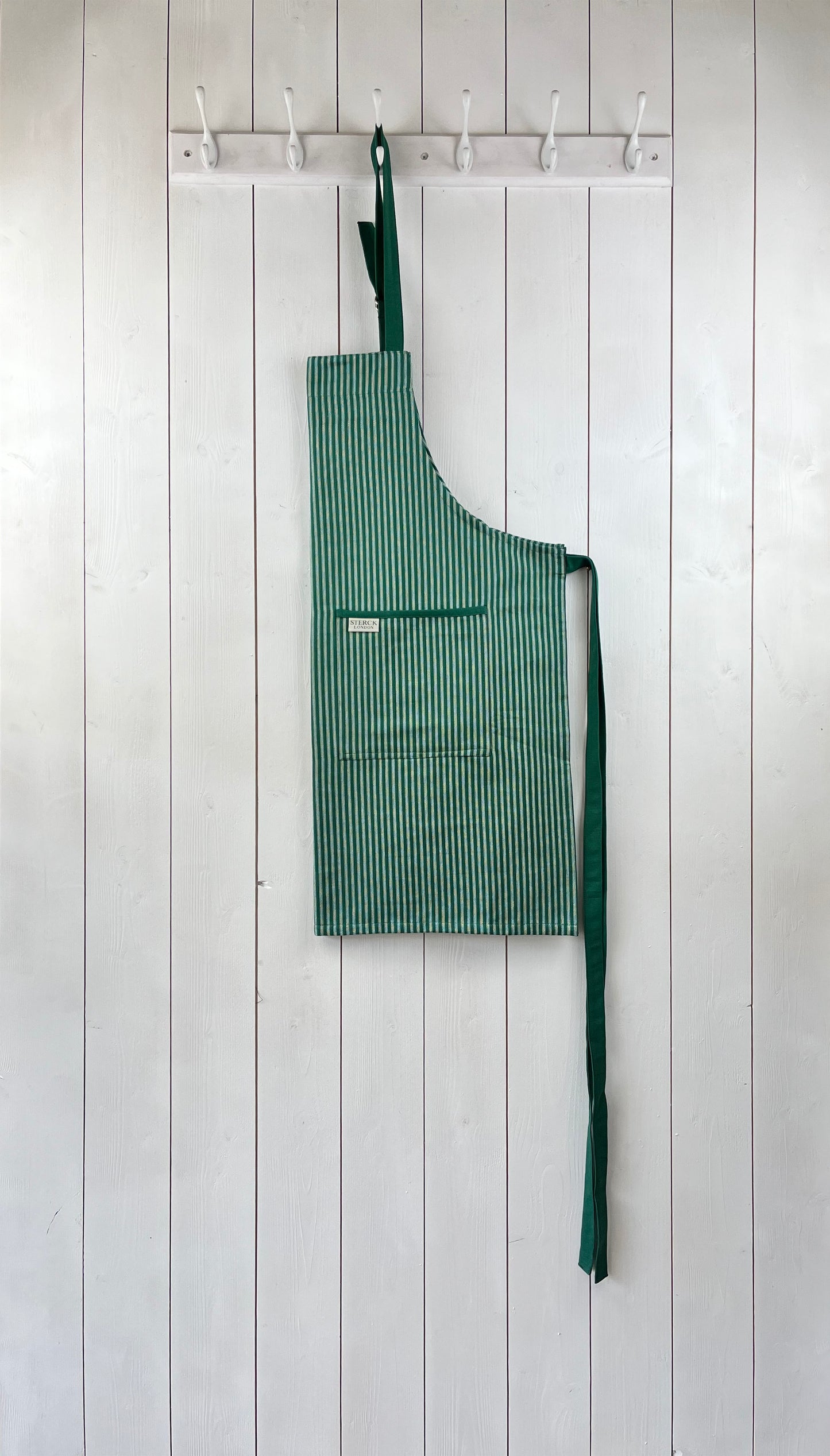 green striped cotton apron with double front pockets, green ties and adjustable neck strap. sterck & co. drum green.