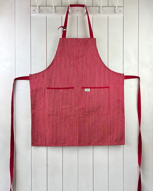 Red striped cotton apron with double front pockets, red ties and adjustable neck strap. Sterck & Co. Drum red.