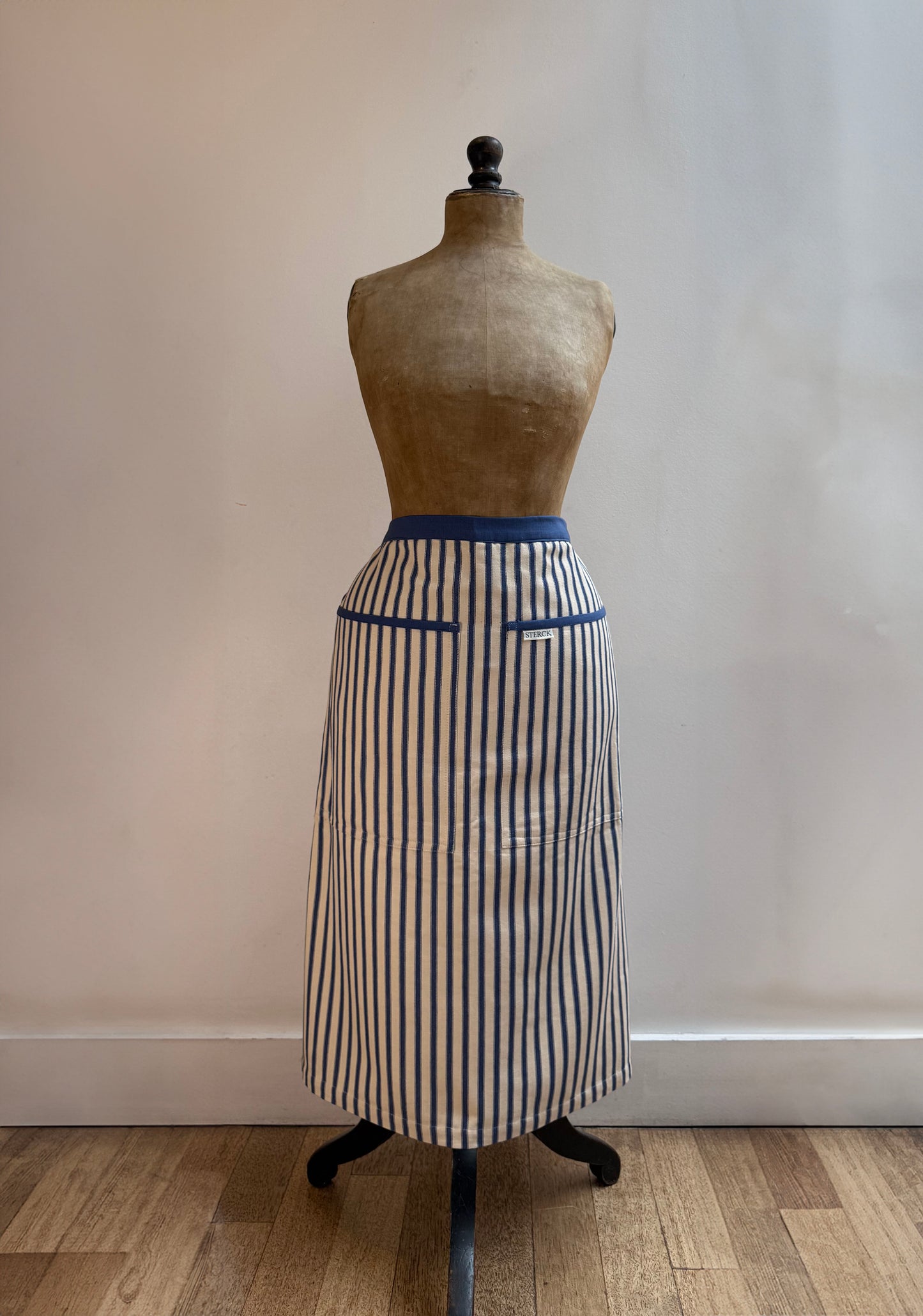 sterck half apron in kolaba blue stripe, modelled by an antique mannequin.