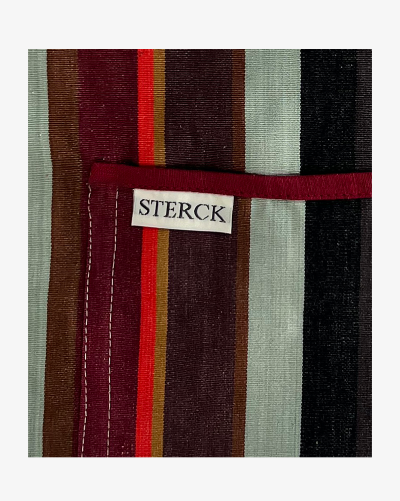 A modern striped cotton apron with double front pockets and adjustable neck strap. Sterck & Co. Close up of fabric and pocket detailing.