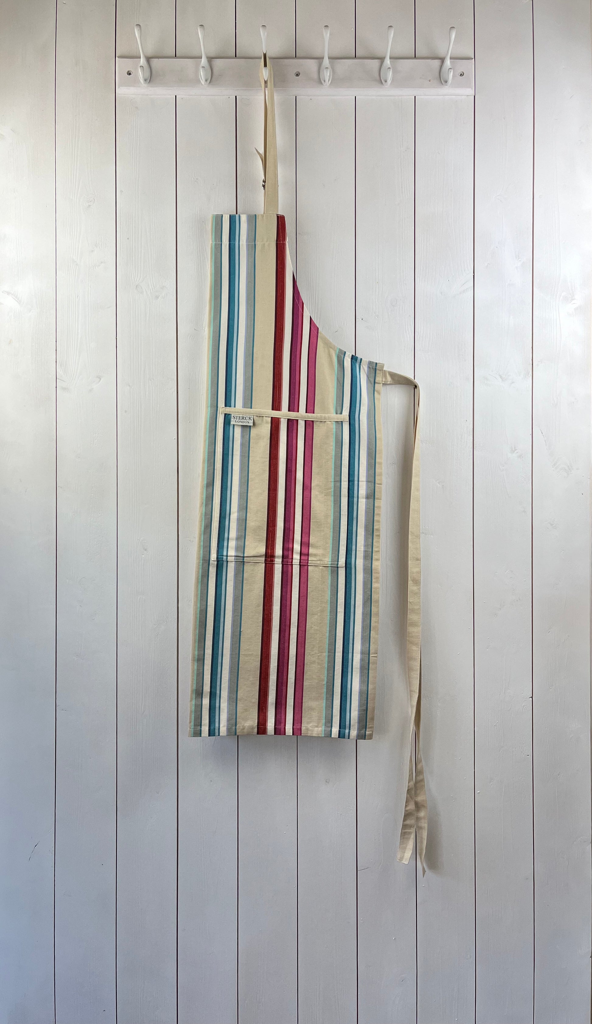 A vibrant striped cotton apron with double front pockets, cream ties and adjustable neck strap. Sterck & Co.