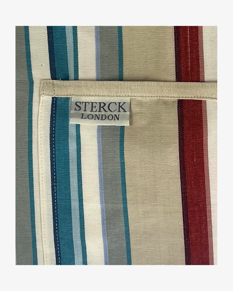 A vibrant striped cotton apron with double front pockets, cream ties and adjustable neck strap. Sterck & Co. Close up of fabric and pocket detailing.