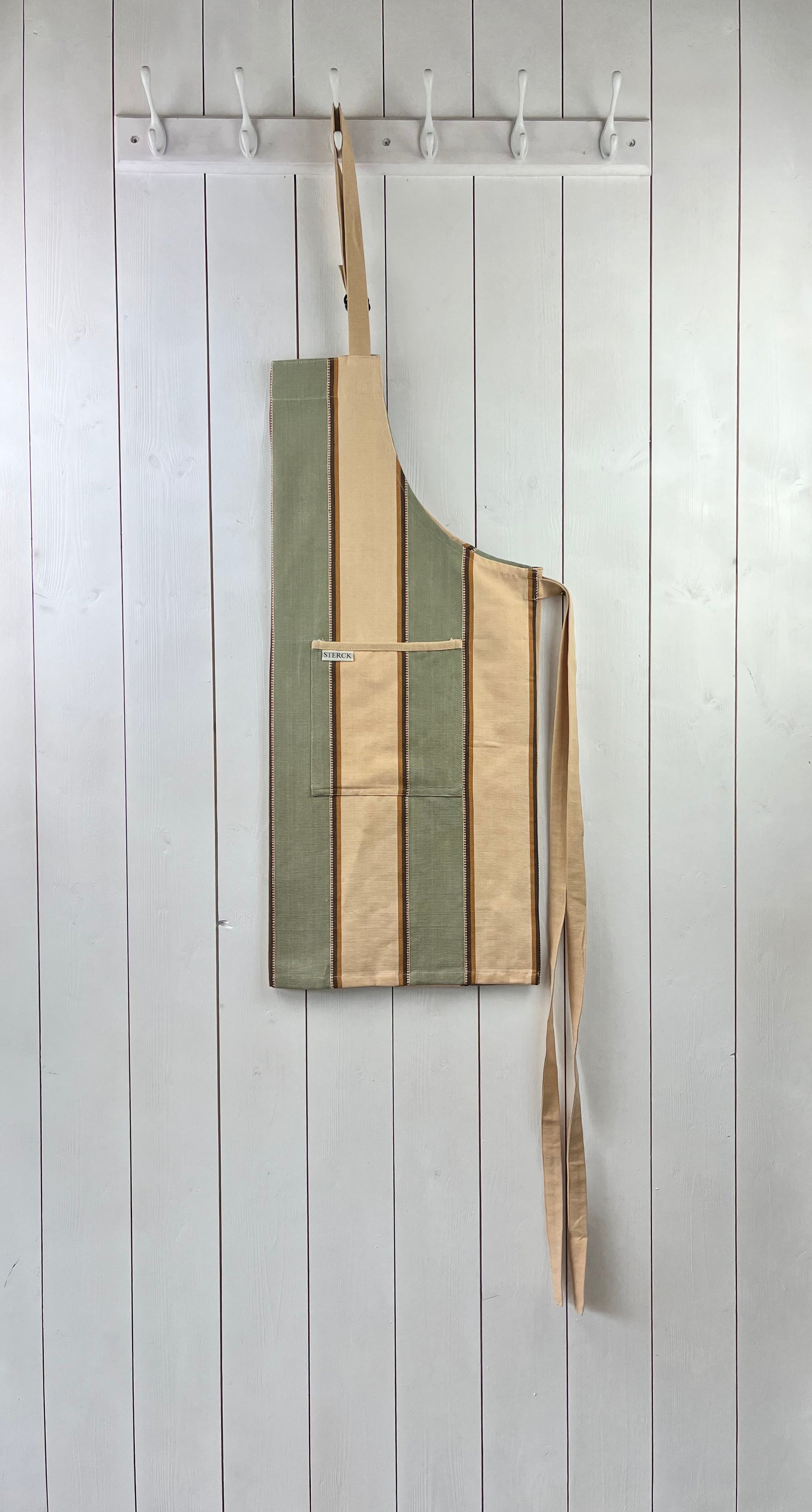 Wide striped, cream, green and brown cotton apron with double pockets, cream ties and adjustable neck strap. Sterck & Co.