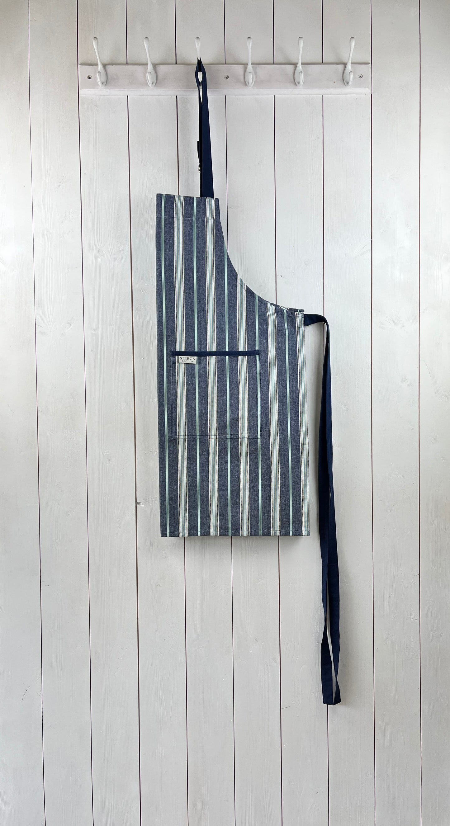 a classic blue striped cotton apron with double front pockets, blue ties and adjustable neck strap.