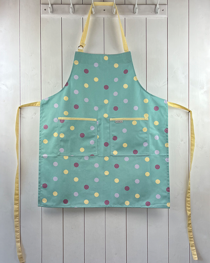 Duck egg blue cotton apron with purple, yellow and mauve spots, yellow ties and adjustable neck strap.