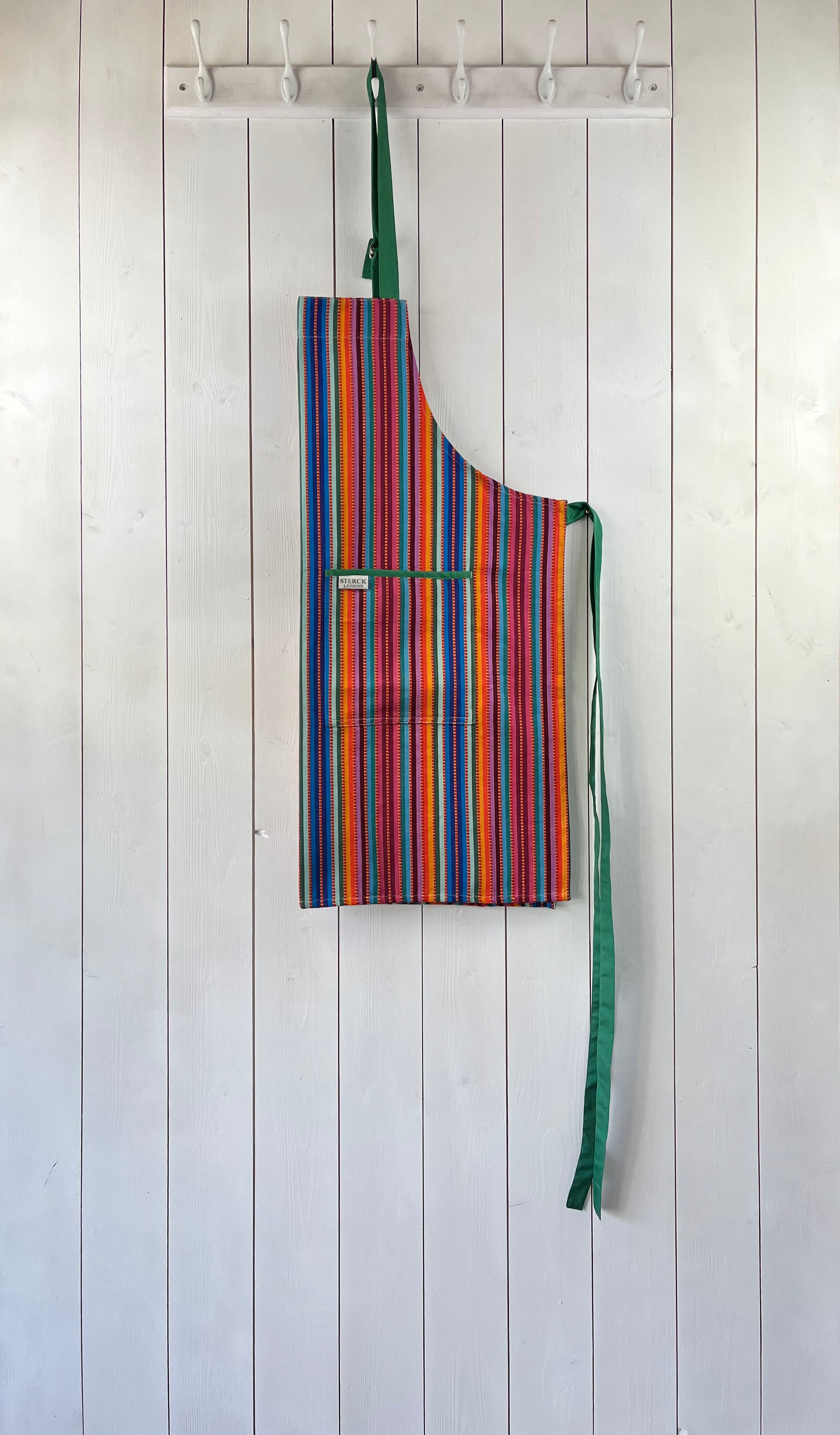 A stripy cotton apron with prominent ticking, two front pockets and adjustable green straps.