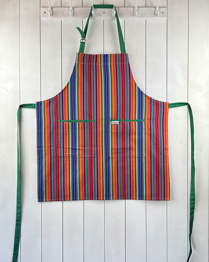 a stripy cotton apron with prominent ticking, two front pockets and adjustable green straps.