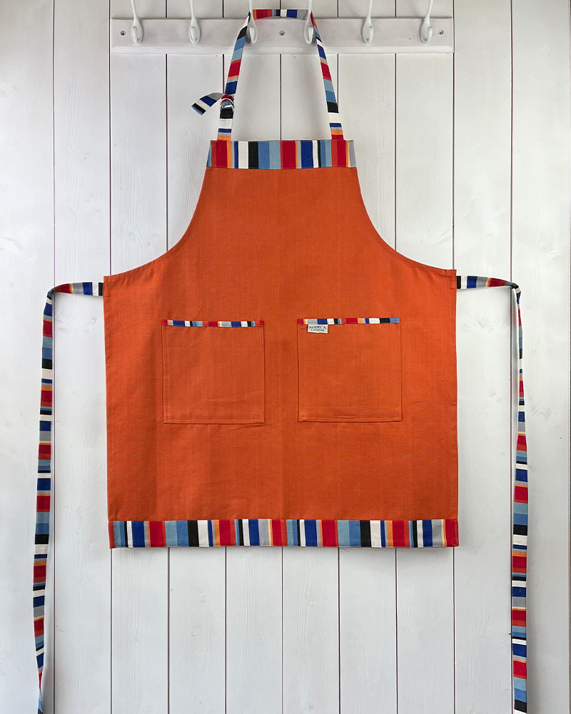 vibrant orange apron with stripey straps and edging. two front pockets and adjustable neck strap.