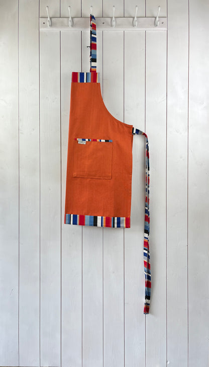 Vibrant orange apron with stripey straps and edging. Two front pockets and adjustable neck strap.